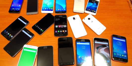 Various used Android smartphones on a wooden table.